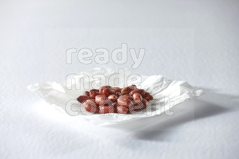 Red skin peanuts on a crumpled piece of paper on a white background in different angles