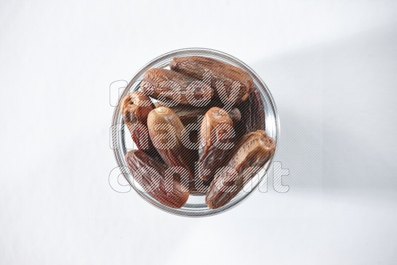 A glass bowl full of dried dates on a white background in different angles