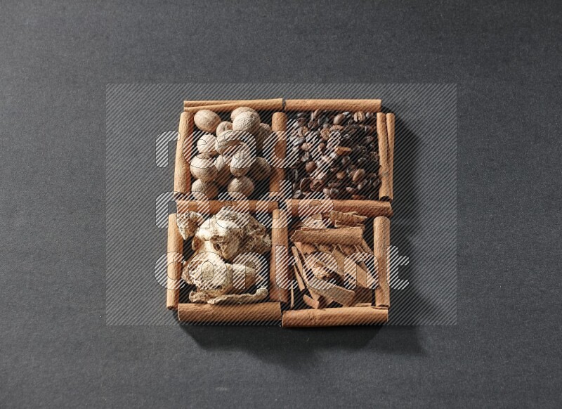 4 squares of cinnamon sticks full of coffee beans, cinnamon, dried ginger and nutmegs on black flooring