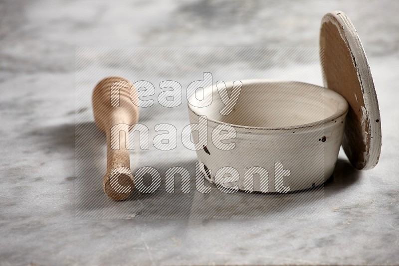 White Pottery Bowl with wooden honey handle on the side with grey marble flooring, 15 degree angle