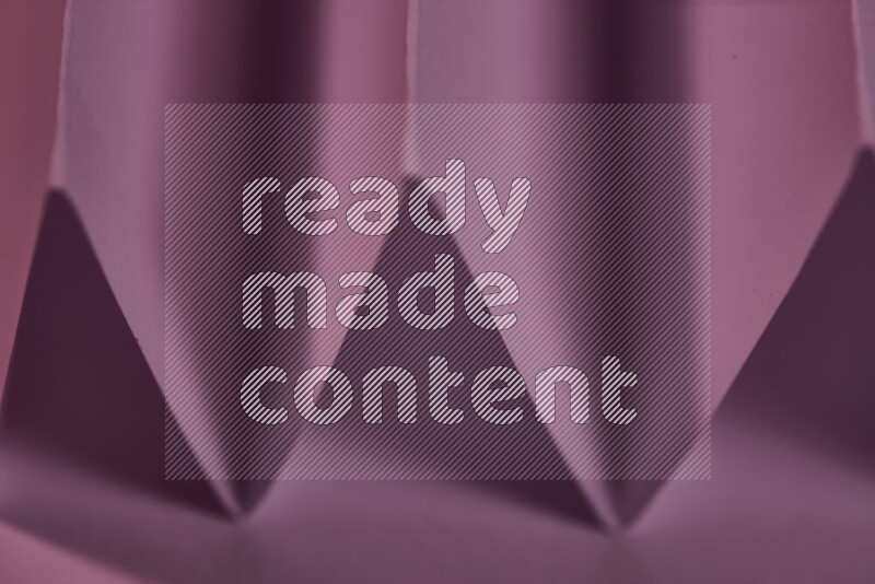 صورة مجردة مقربة تظهر طيات ورقية هندسية حادة بتدرجات اللون الارجواني