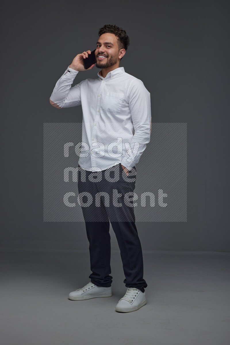A man wearing smart casual talking in the phone eye level on a gray background