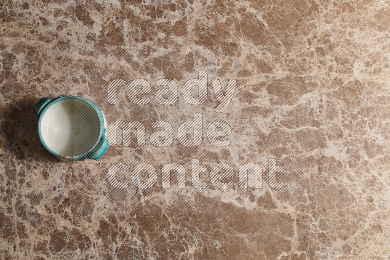 A multicolored pottery bowl on beige marble background