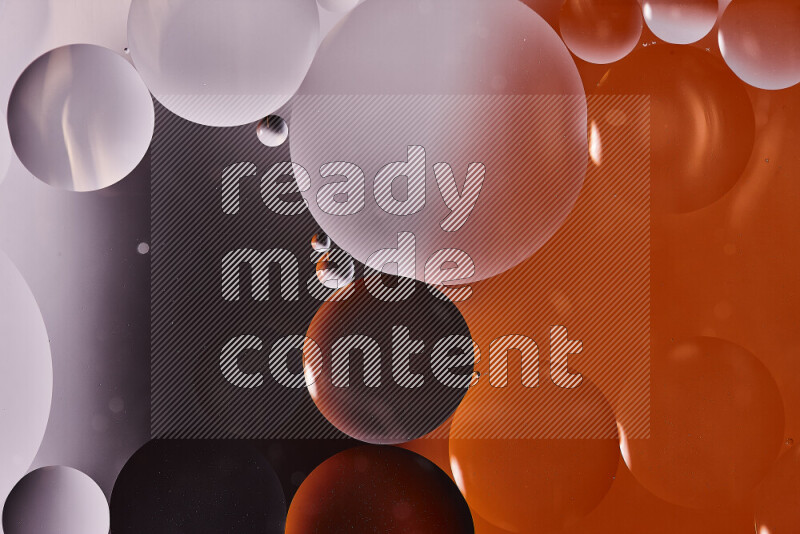 Close-ups of abstract oil bubbles on water surface in shades of black and orange