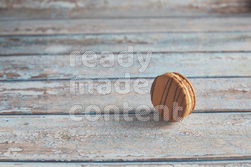 45º Shot of light brown Almond Cream macaron on light blue wooden background
