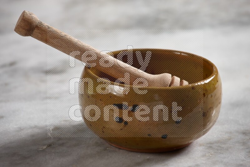 Multicolored pottery bowl with wooden honey dipper in it on grey marble background