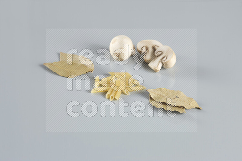 Raw pasta with different ingredients such as cherry tomatoes, garlic, onions, red chilis, black pepper, white pepper, bay laurel leaves, rosemary, cardamom and mushrooms on light blue background