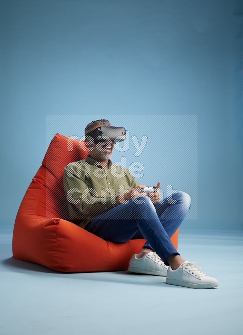 A man sitting on an orange beanbag and gaming with VR