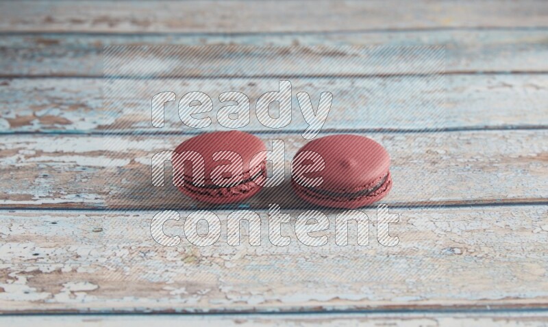 45º Shot of two Red Cherry macarons on light blue wooden background
