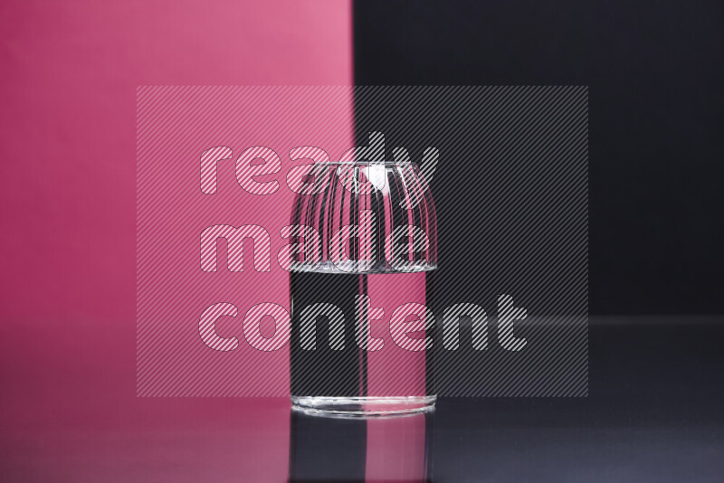 The image features a clear glassware filled with water, set against pink and black background