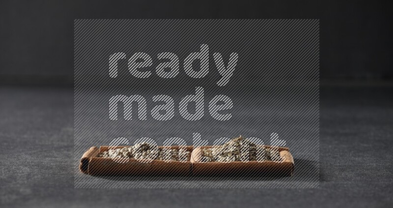 مربعان من أعواد القرفة ممتلئان بحبوب الفلفل الأبيض وحبوب الكمون علي خلفية سوداء