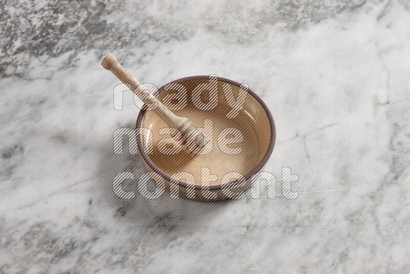 Beige Pottery oven bowl with wooden honey handle on the side with grey marble flooring, 65 degree angle