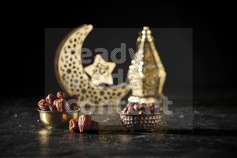 Dates in a metal bowl with hazelnuts beside golden lanterns in a dark setup