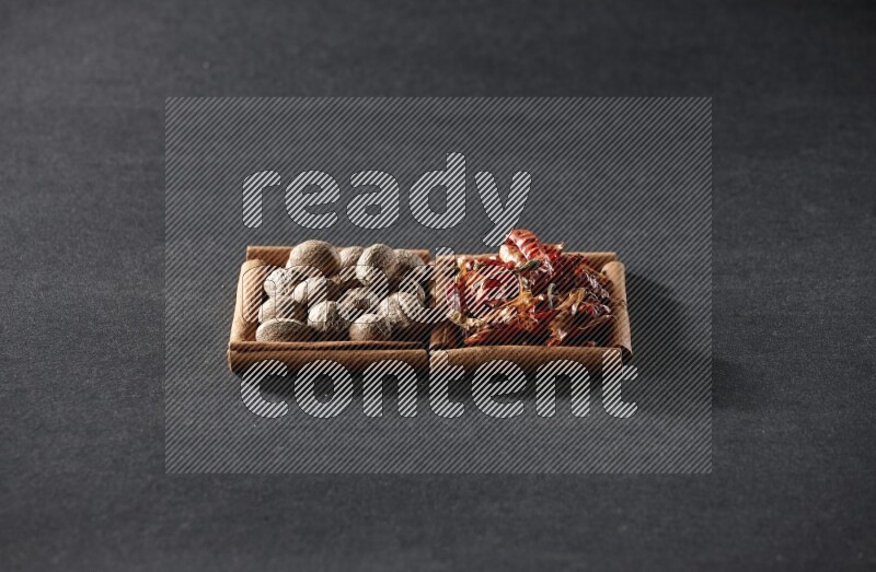 مربعان من أعواد القرفة ممتلئان بجوزة الطيب والفلفل الحار المجفف علي خلفية سوداء