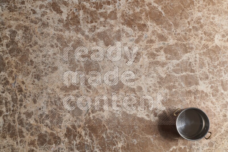 A small copper pot on beige marble background