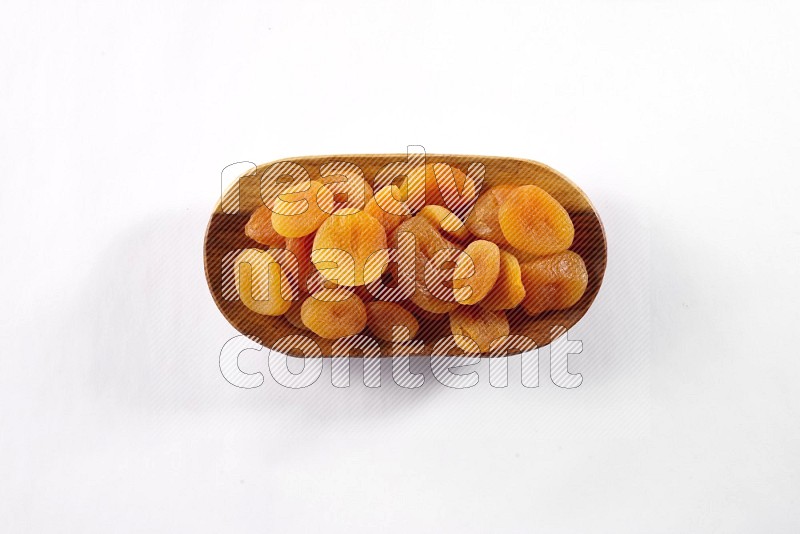 Dried apricots in a wooden plate on white background