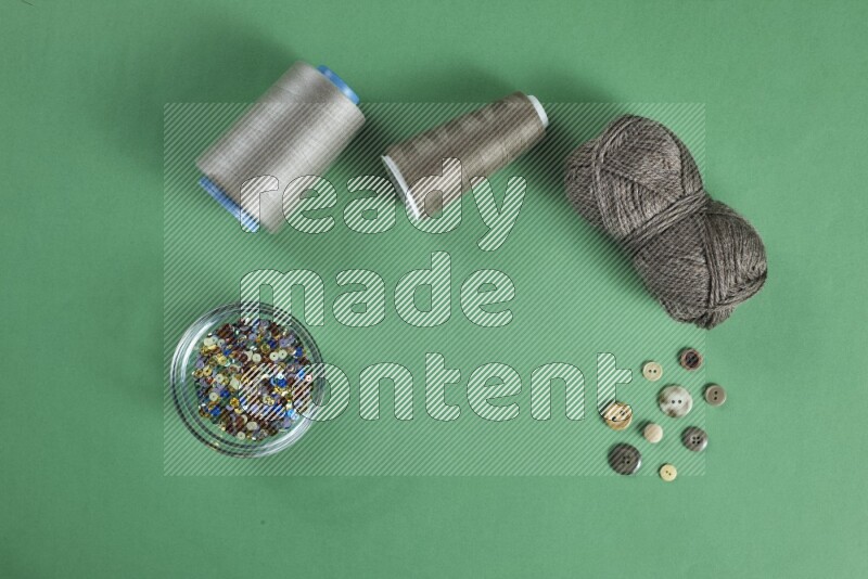 A brown collection of sewing and tailoring tools arranged on a green background