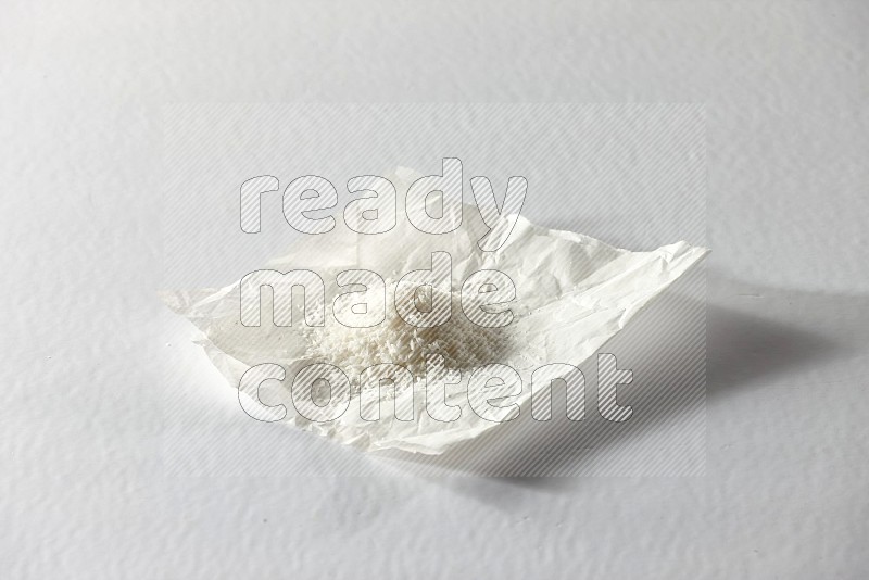 Desiccated coconut on a piece of paper on a white background in different angles