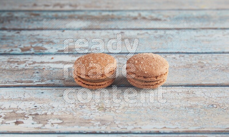 45º Shot of two Brown Hazelnuts macarons on light blue wooden background