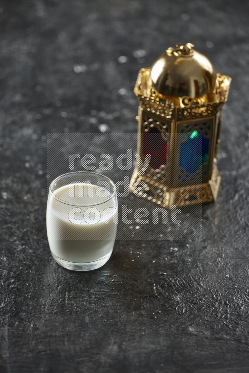 A golden lantern with different drinks, dates, nuts, prayer beads and quran on textured black background