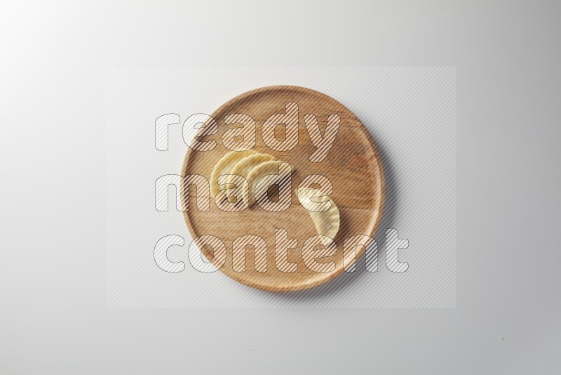 Four Sambosas on a wooden round plate on a white background