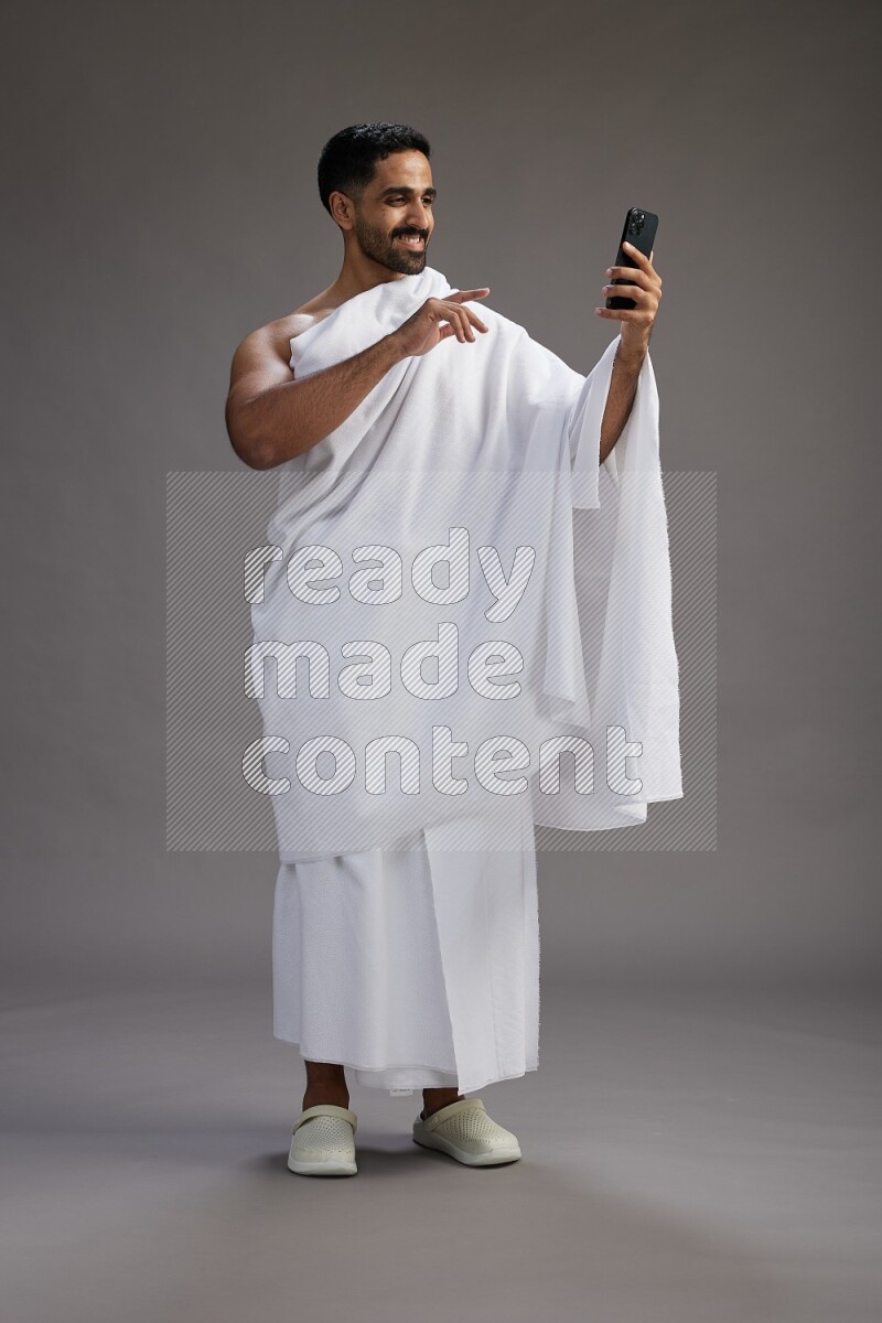 A man wearing Ehram Standing taking selfie on gray background