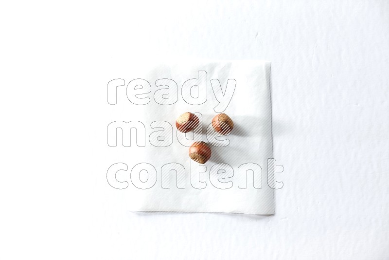 3 hazelnuts on a piece of paper on a white background in different angles