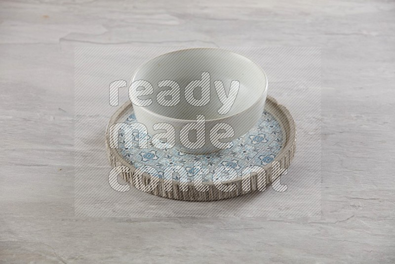white pottery round bowl on top of multi color round ceramic plate and chopsticks, on grey textured countertop