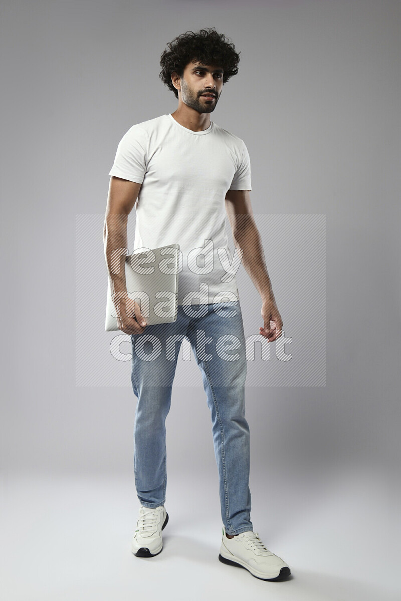 A man wearing casual standing and holding a laptop on white background