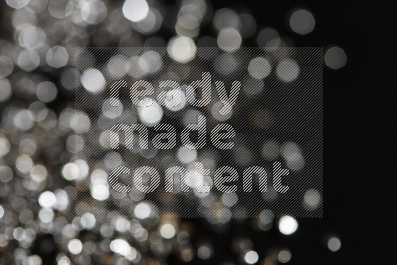 Silver shimmering fragments of glass scattered on a black background