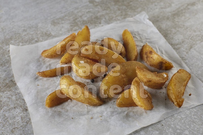 wedges potato on parchment paper on grey textured counter top