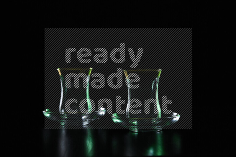 Glassware with rim light in green and white against black background