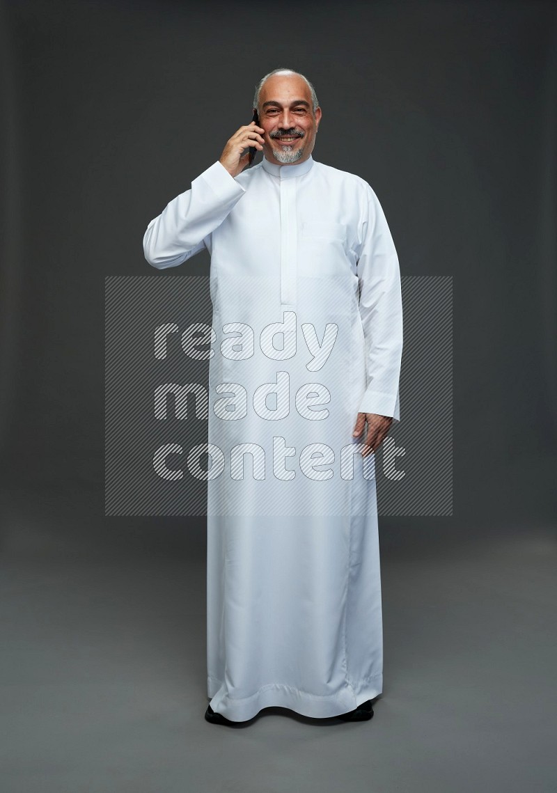 Saudi man without shomag Standing talking on phone on gray background