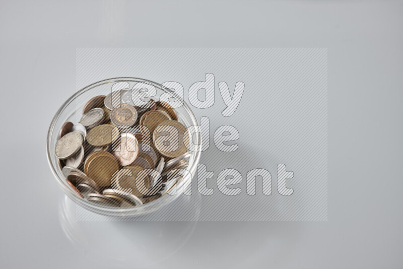 Random old coins in a glass bowl on grey background