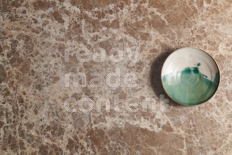 A decorative pottery plate on beige marble background