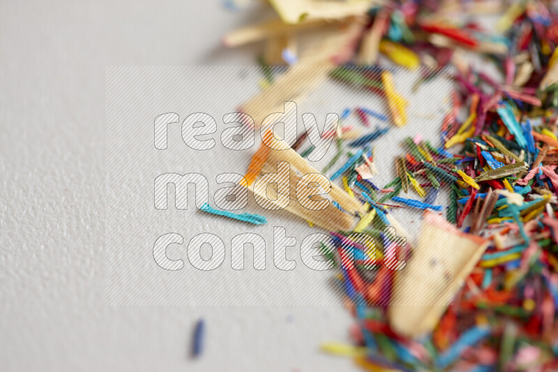This image showcases a vibrant multicolored pencil shavings scattered on grey background