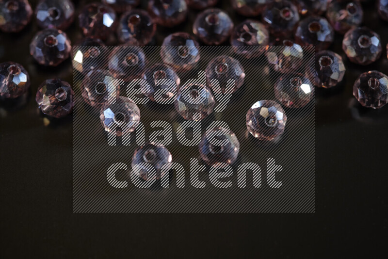Rose transparent crystal beads scattered on a black background