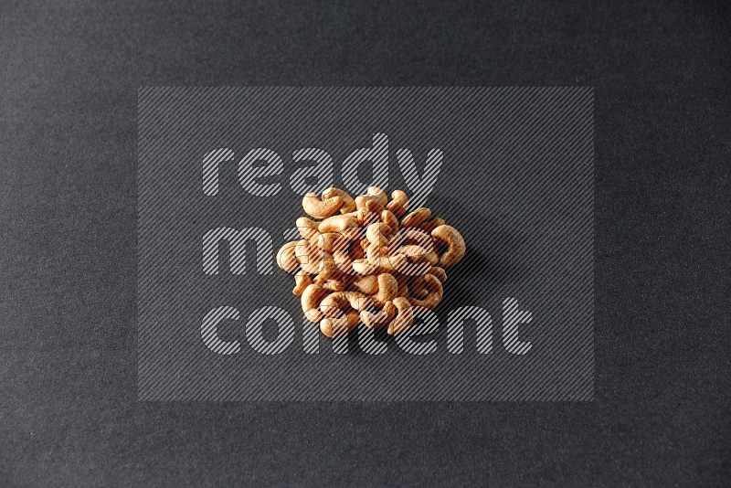 A bunch of cashews on a black background in different angles