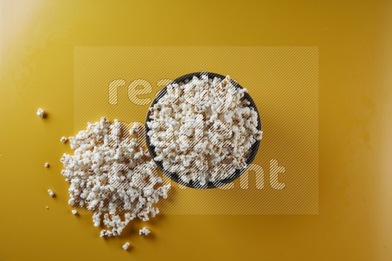 A copper ceramic bowl full of popcorn with popcorn beside it on a yellow background in different angles