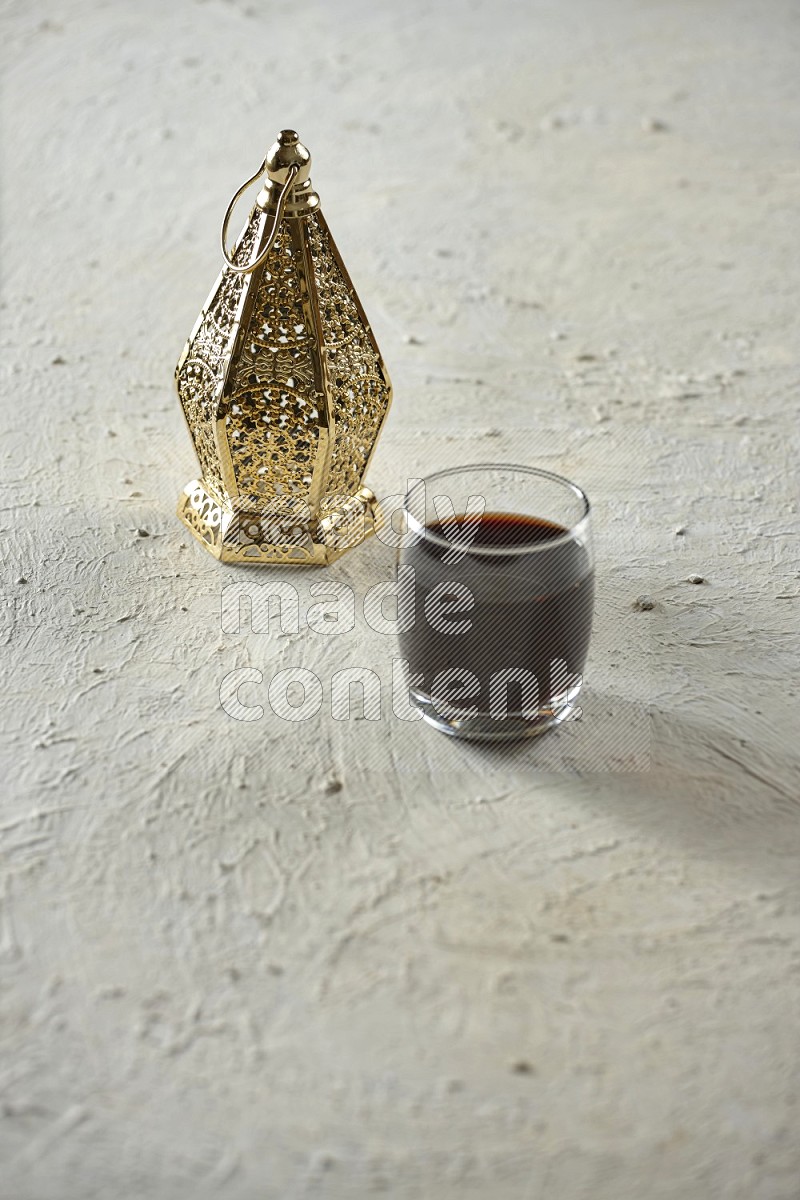 A golden lantern with different drinks, dates, nuts, prayer beads and quran on textured white background