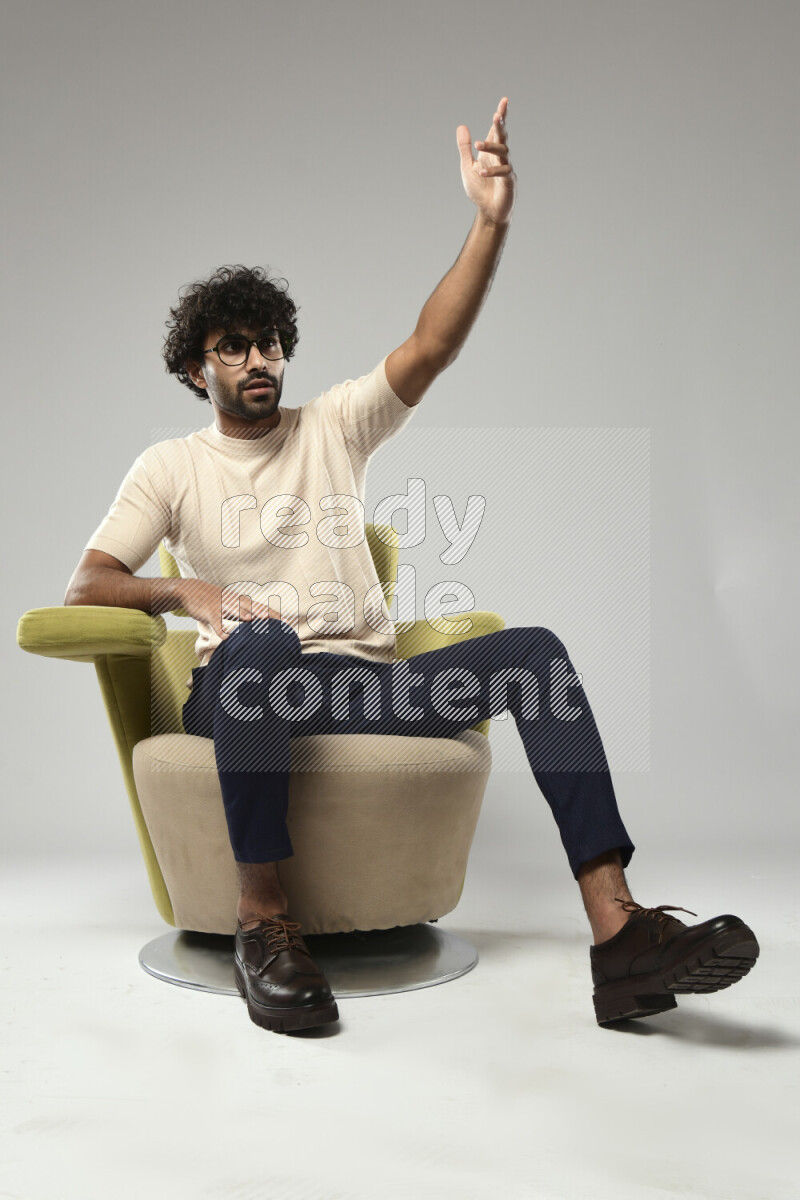 A man wearing casual sitting on a chair making a hand gesture on white background
