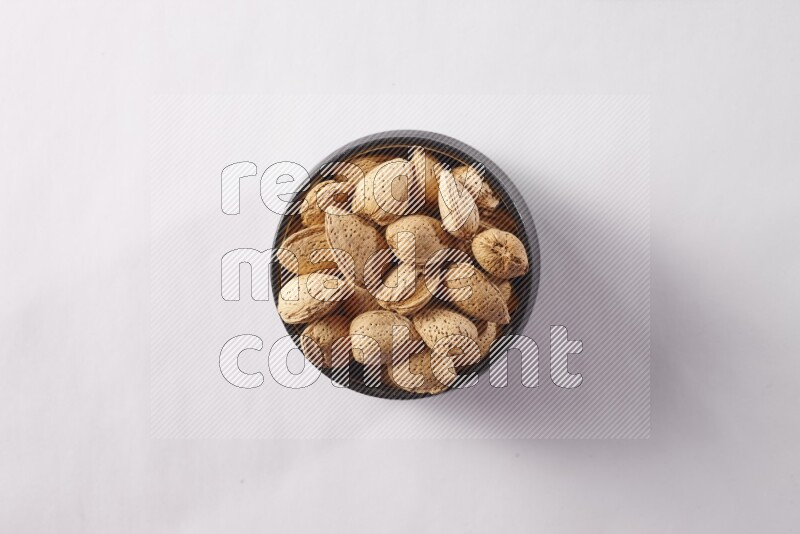 Almonds in a black pottery bowl on white background