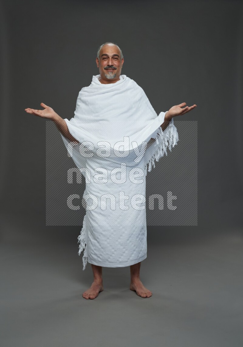 A man wearing Ehram Standing Interacting with the camera on gray background