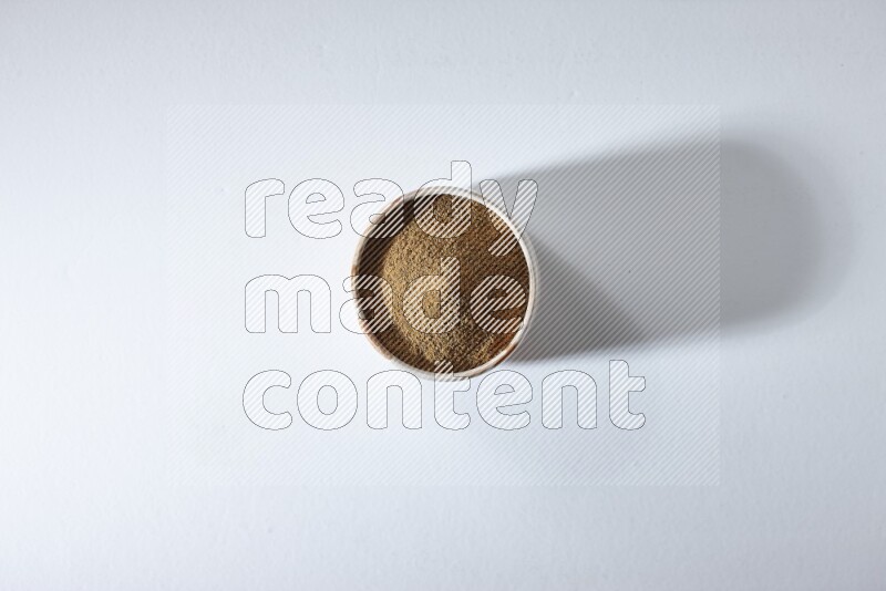 وعاء بيج ممتلئ ببودرة الكمون على خلفية بيضاء