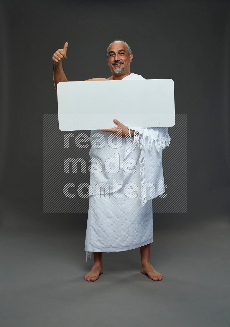 A man wearing Ehram Standing holding social media sign on gray background