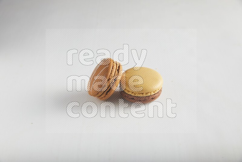 45º Shot of of two assorted Brown Irish Cream, and Yellow, and Brown Chai Latte macarons on white background