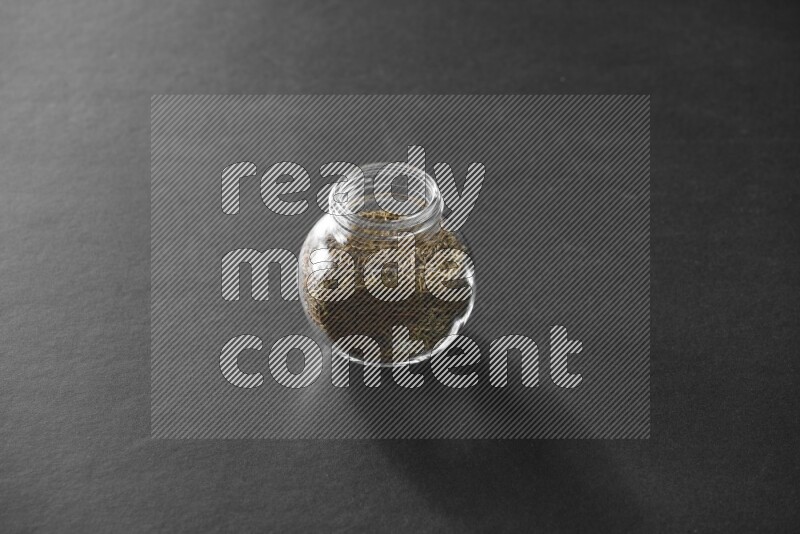 كمون في وعاء زجاجي علي خلفية سوداء
