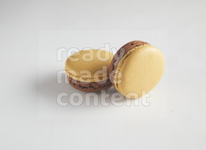 45º Shot of two Yellow and Brown Chai Latte macarons on white background