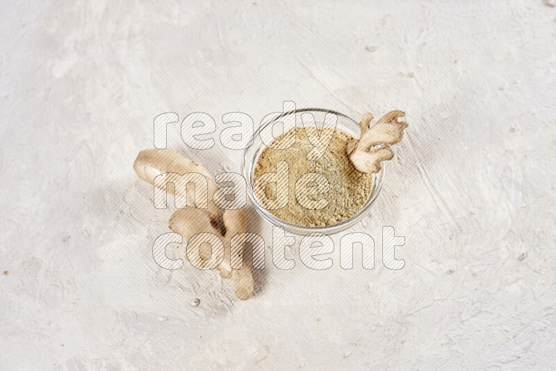 A glass bowl full of ground ginger powder on white background
