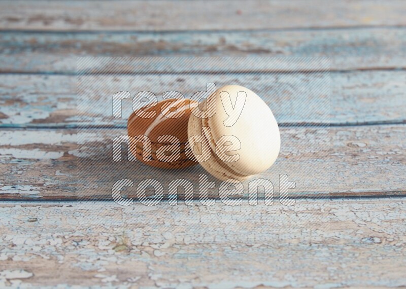 45º Shot of of two assorted Brown Irish Cream, and White Caramel fleur de sel macarons on light blue background